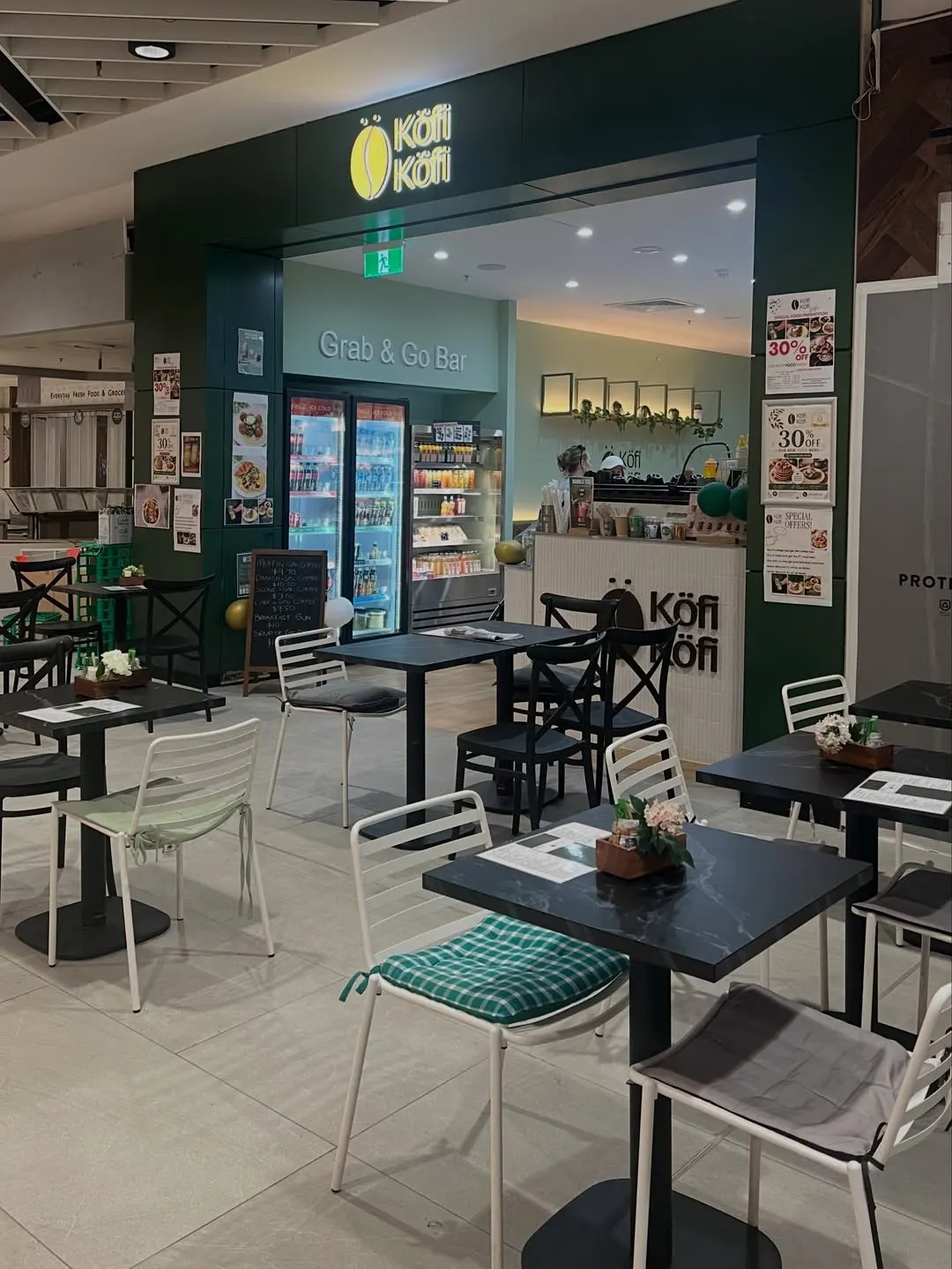 Inside the Köfi Köfi cafe: tables, the drinks fridges and the green Köfi Köfi sign
