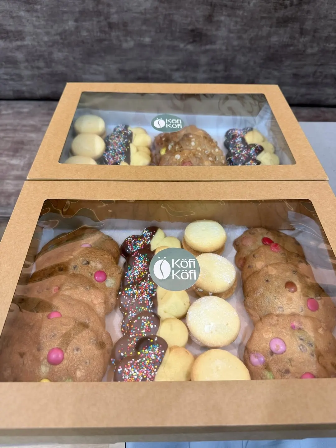 Two Köfi Köfi catering boxes filled with cookies, shortbread and chocolate-dipped treats
